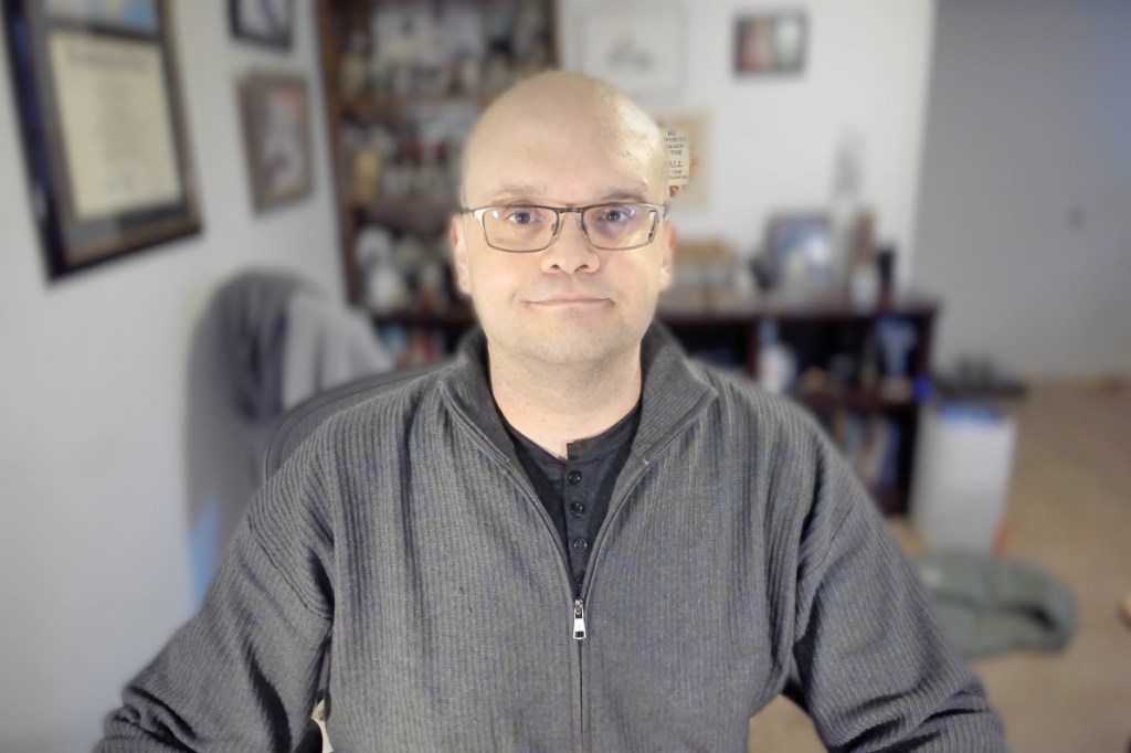 Dr. Andrew Joseph Pegoda. Dr. Pegoda is bald, wears glasses, and has a black shirt on under a dark gray jacket.